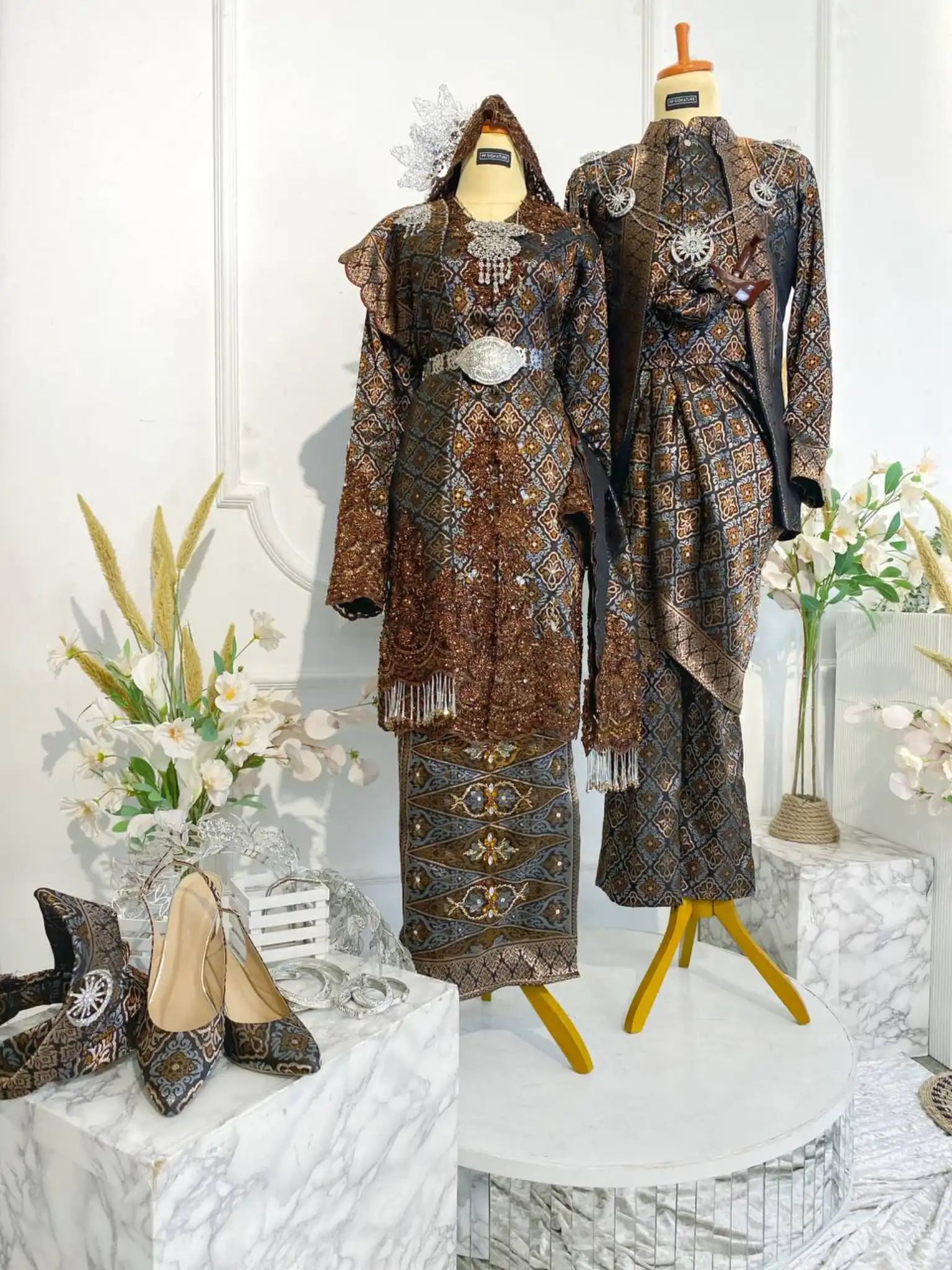 Rent the DARAWATI Baju Sanding Dark Brown Songket Kebaya with Selempang Sulam Biku from Butik Pengantin PP Signature. Perfect for a wedding reception, this dress combines Songket 3D fabric with intricate silver and chrome embroidery.